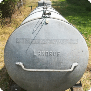 Galvanized steel tank trailer parked on grass